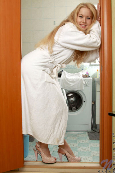 Blonde teen removes a robe as she gets naked in the bathroom to shower Image #1