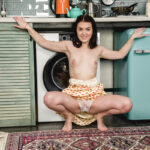 Dark-haired teen Ellie gets completely naked on a rug in her kitchen